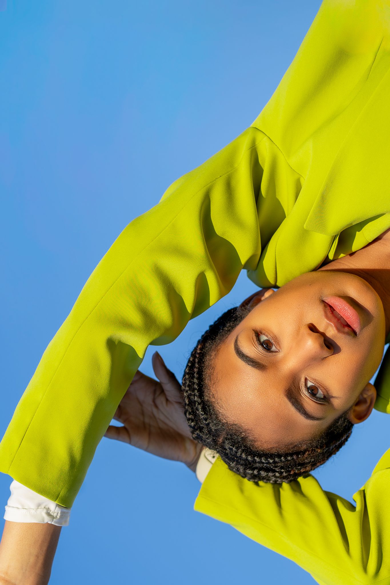Creative portrait in neon yellow jacket against blue background.