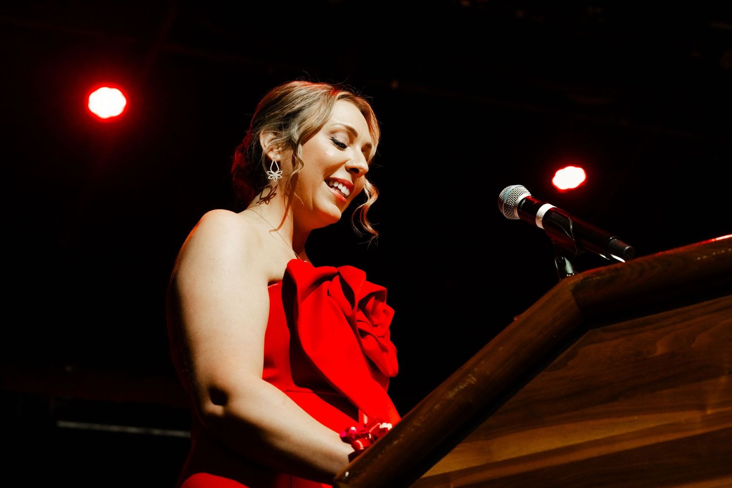 Performer in red dress singing at piano during elegant evening entertainment.