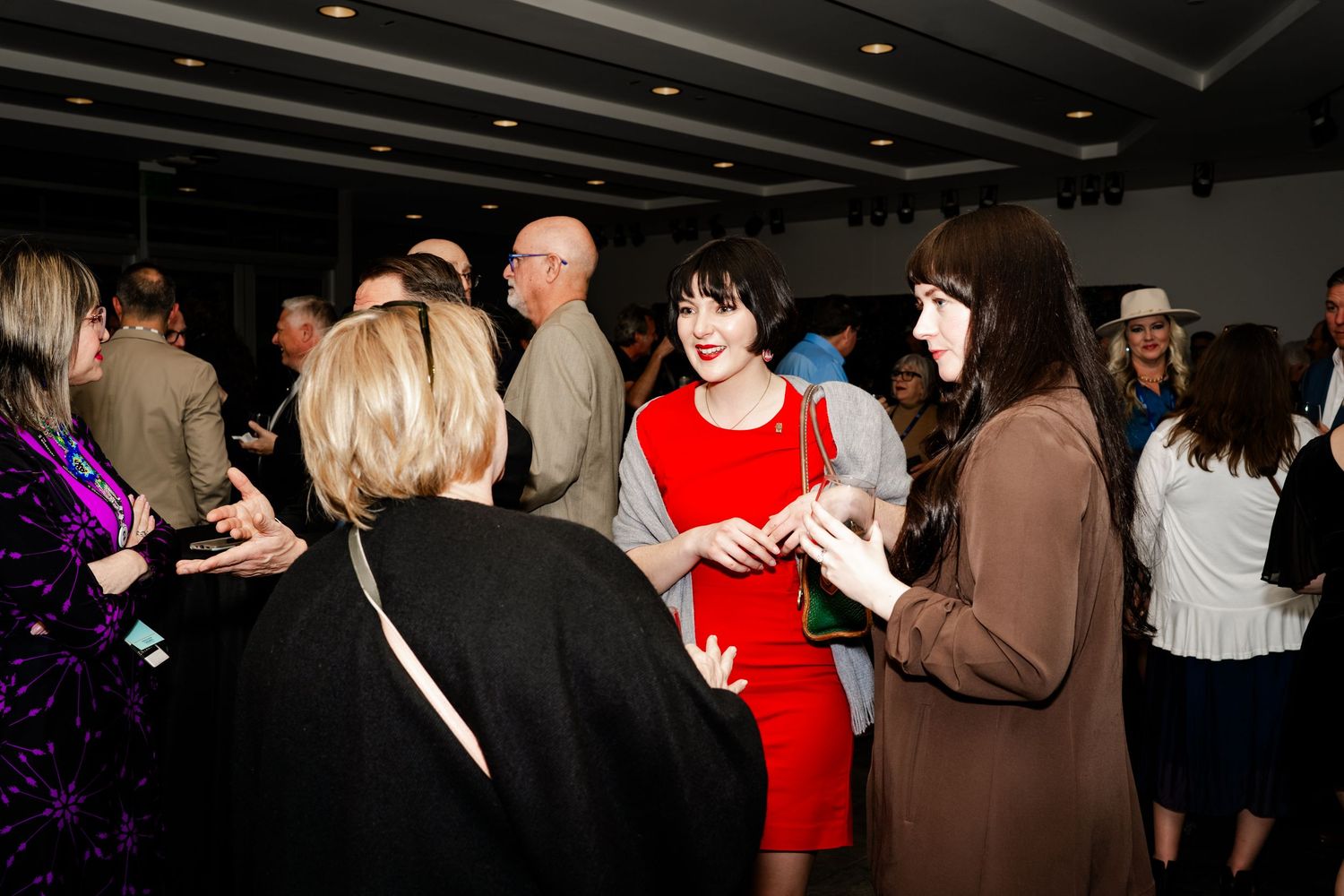 Conference attendees networking in a dark venue with ambient lighting.
