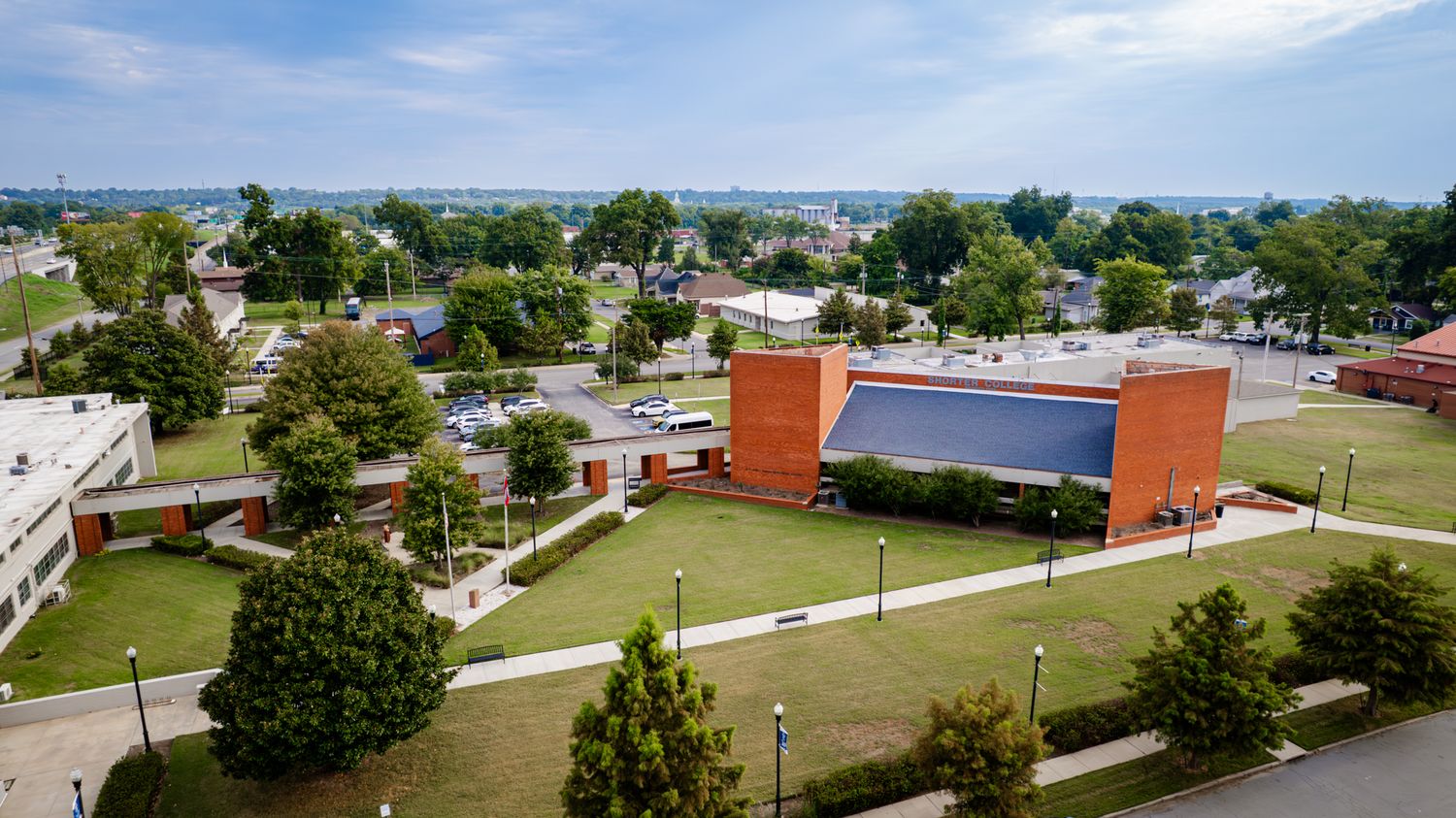 Panoramic aerial view of a suburban campus with buildings and green spaces on a sunny day.