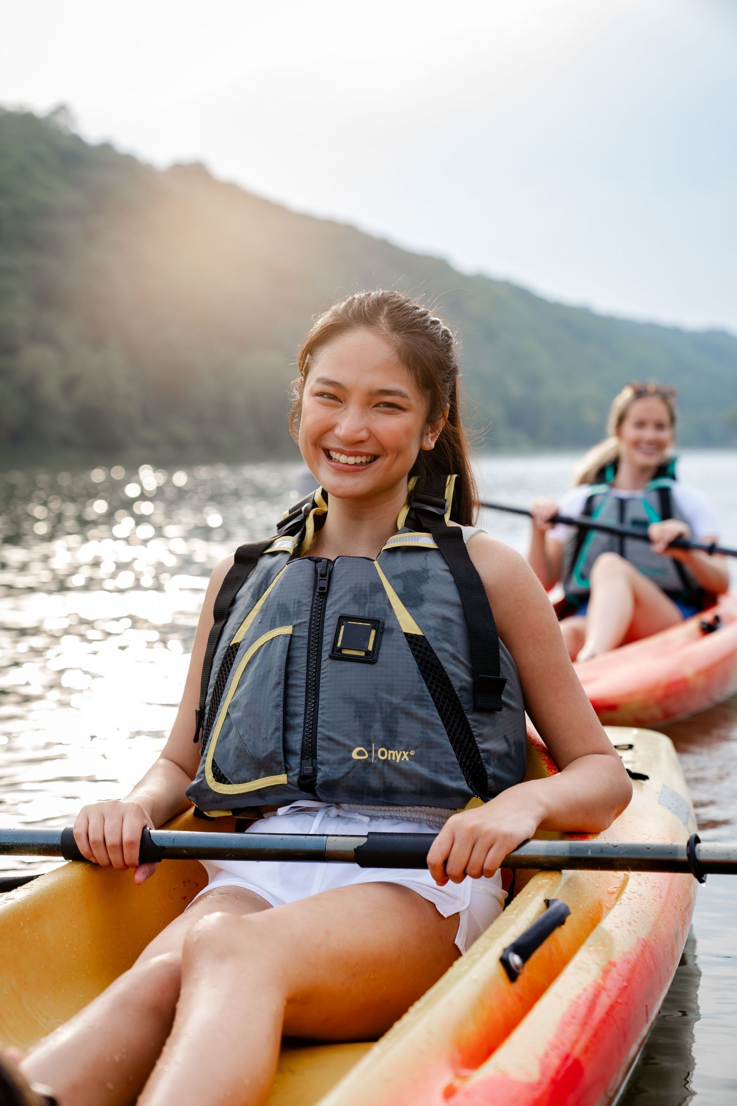 Kayakers enjoying a sunny day on the lake with mountains in background.