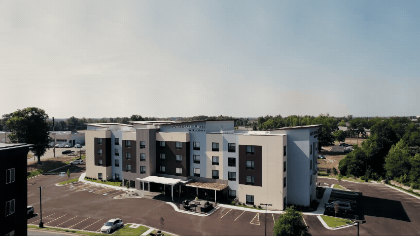Modern apartment complex with white and gray exterior design and parking area.