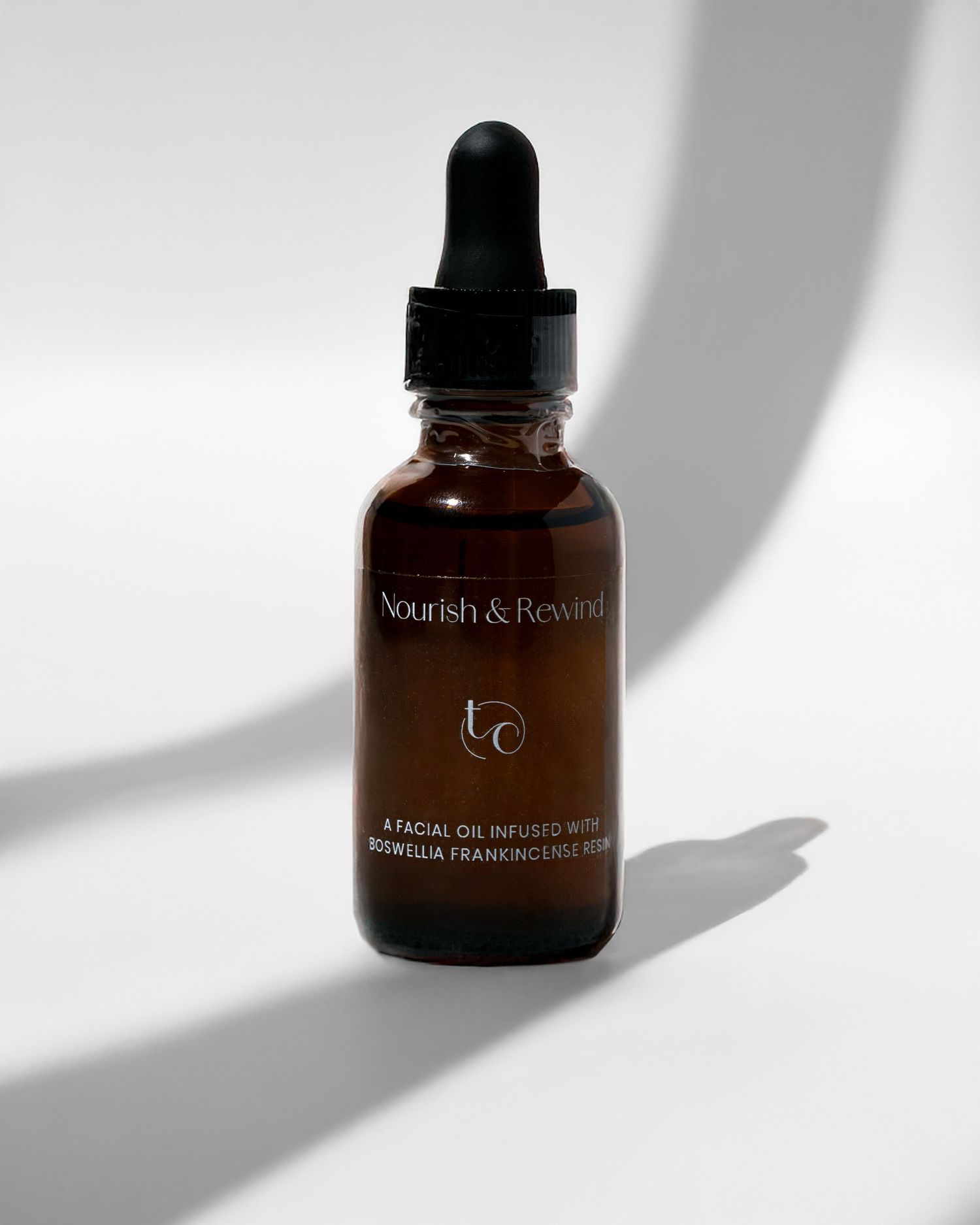 Amber glass dropper bottle with Nourish & Restore label casting dramatic shadow.