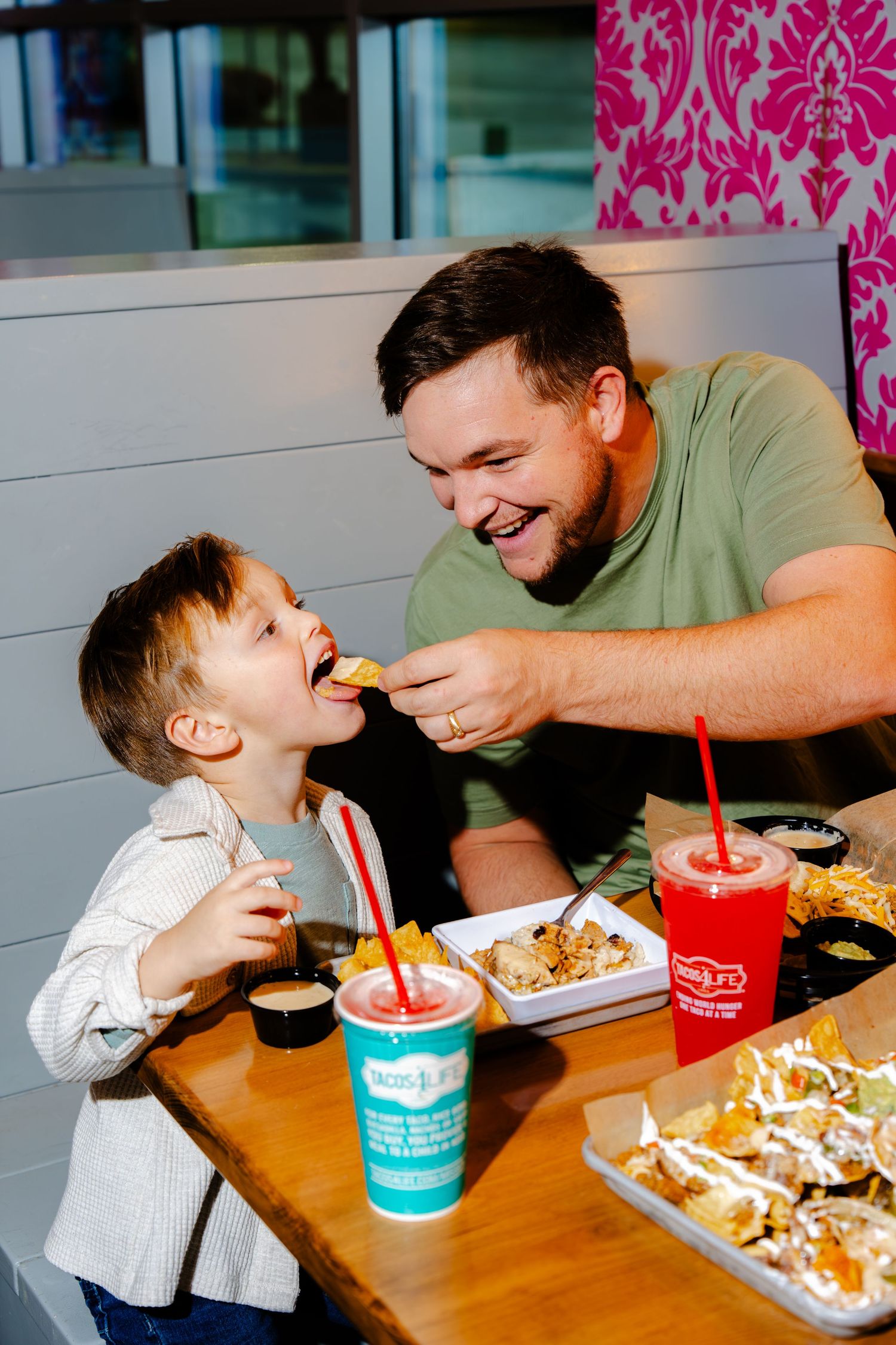 Family sharing laughs and food at casual restaurant with turquoise cups.