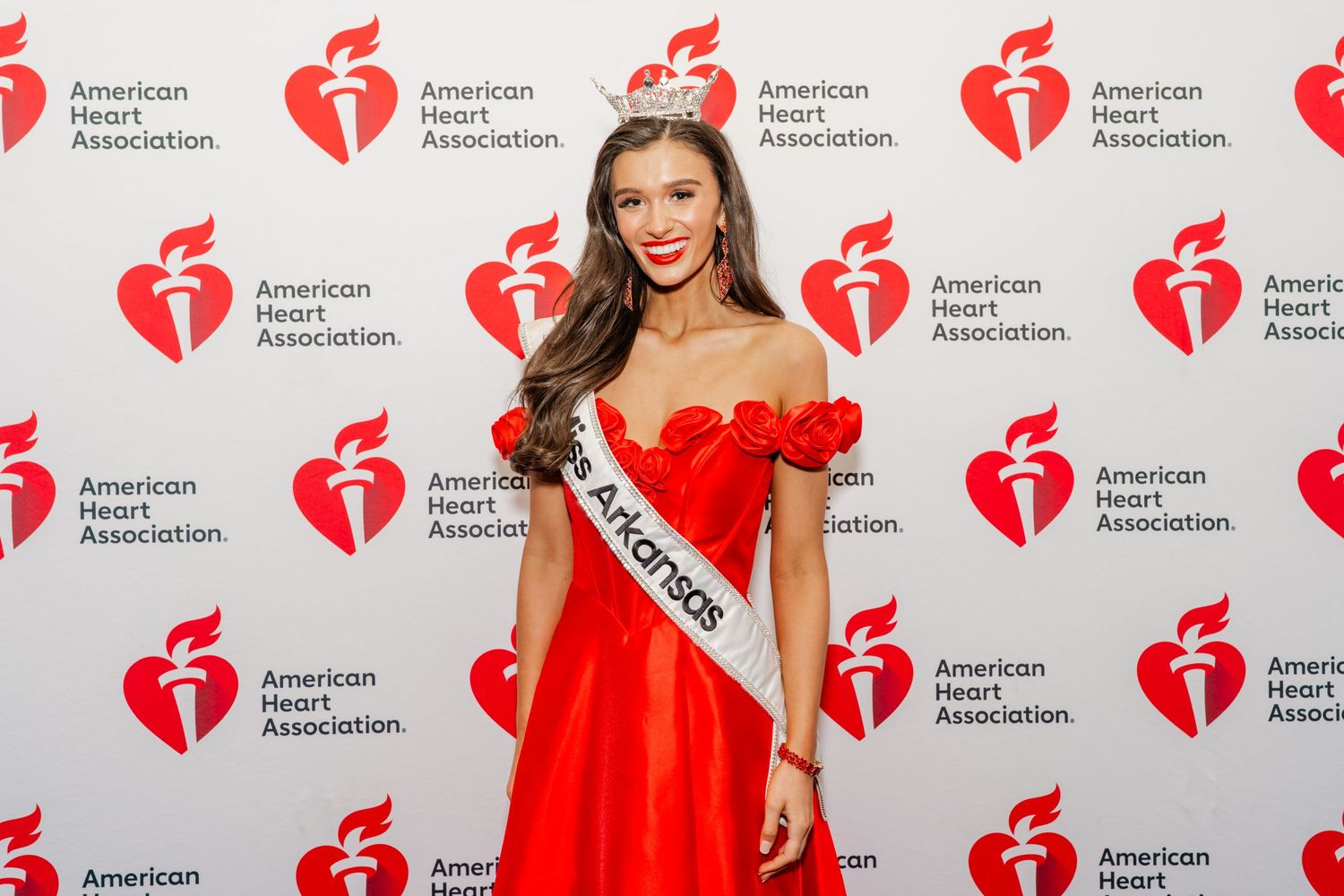 American Heart Association step-and-repeat banner wall with red heart logos at formal event.