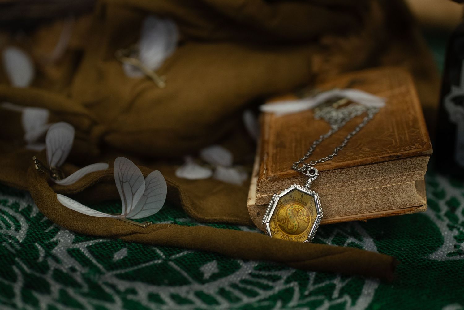 Vintage leather book with antique pendant necklace and delicate white flowers. harry potter. Slytherin Horcrux