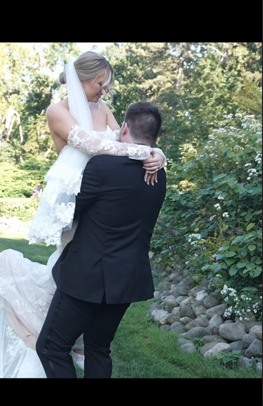 Wedding couple embracing in garden setting with natural stone landscaping.