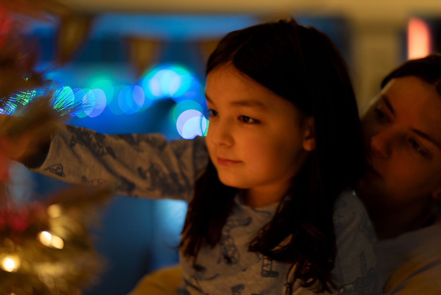Child watching something with bokeh lights in the background creating a magical nighttime atmosphere. Christmas. New years celebration.
