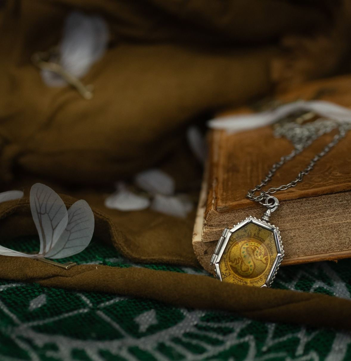 Artistic composition of antique book with hexagonal pendant and butterfly accents. harry potter. Slytherin Horcrux