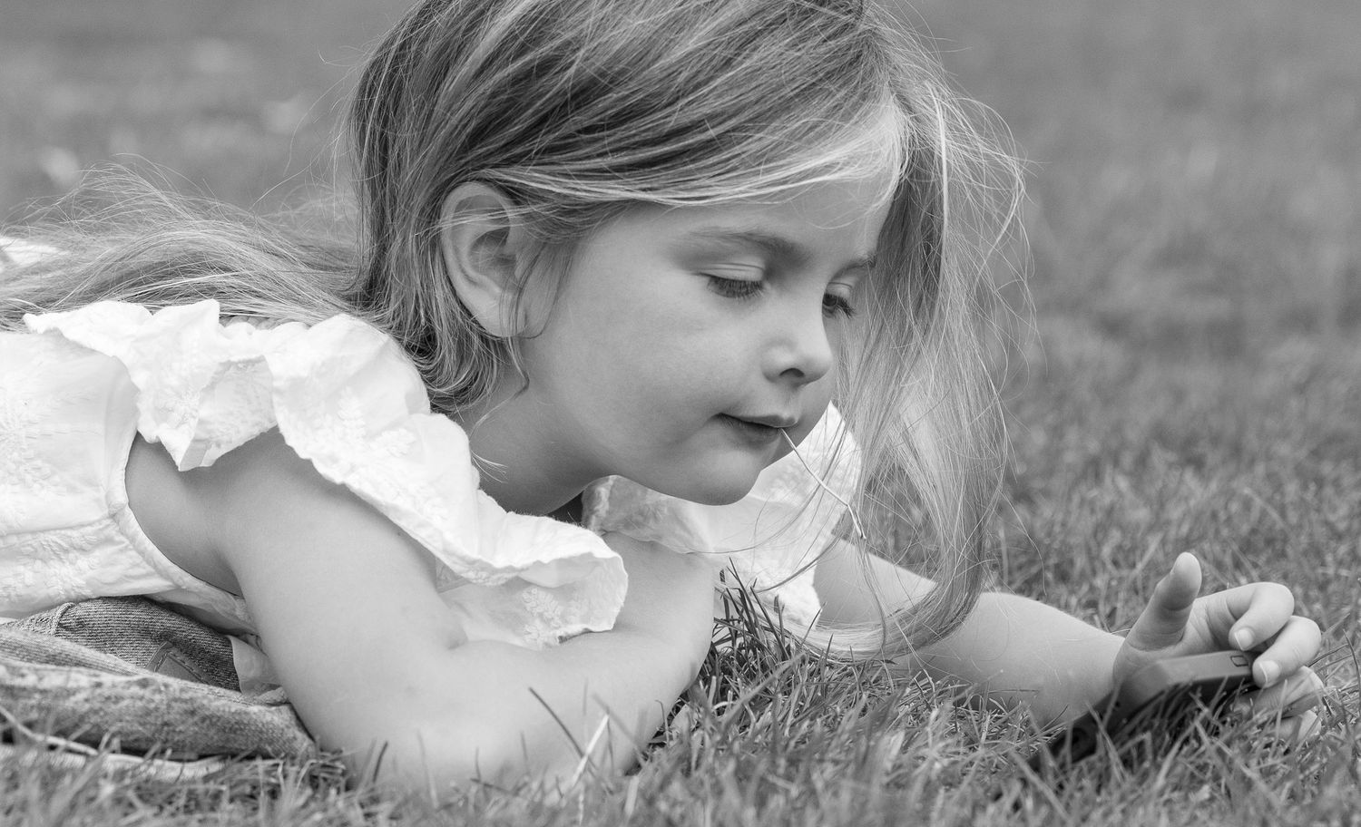 A black and white photo showing a child lying on the grass.