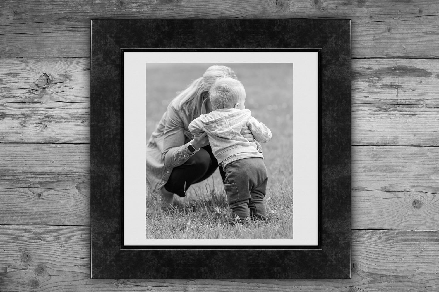 A series of framed black and white photographs arranged on a rustic wooden wall display.