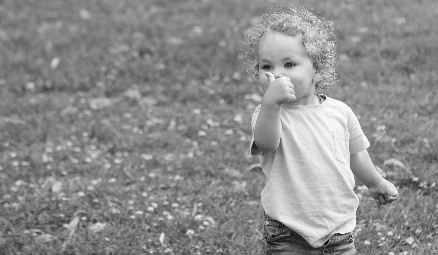 A candid black and white photo of a toddler playing outdoors.