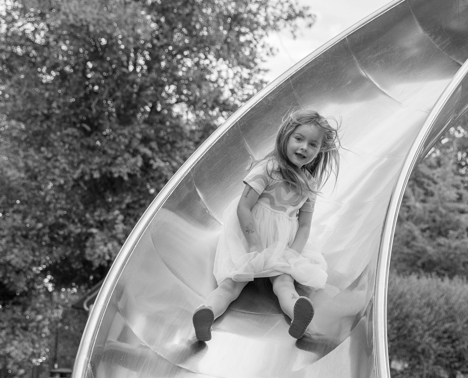 A playful moment on a playground slide captured in black and white photography.