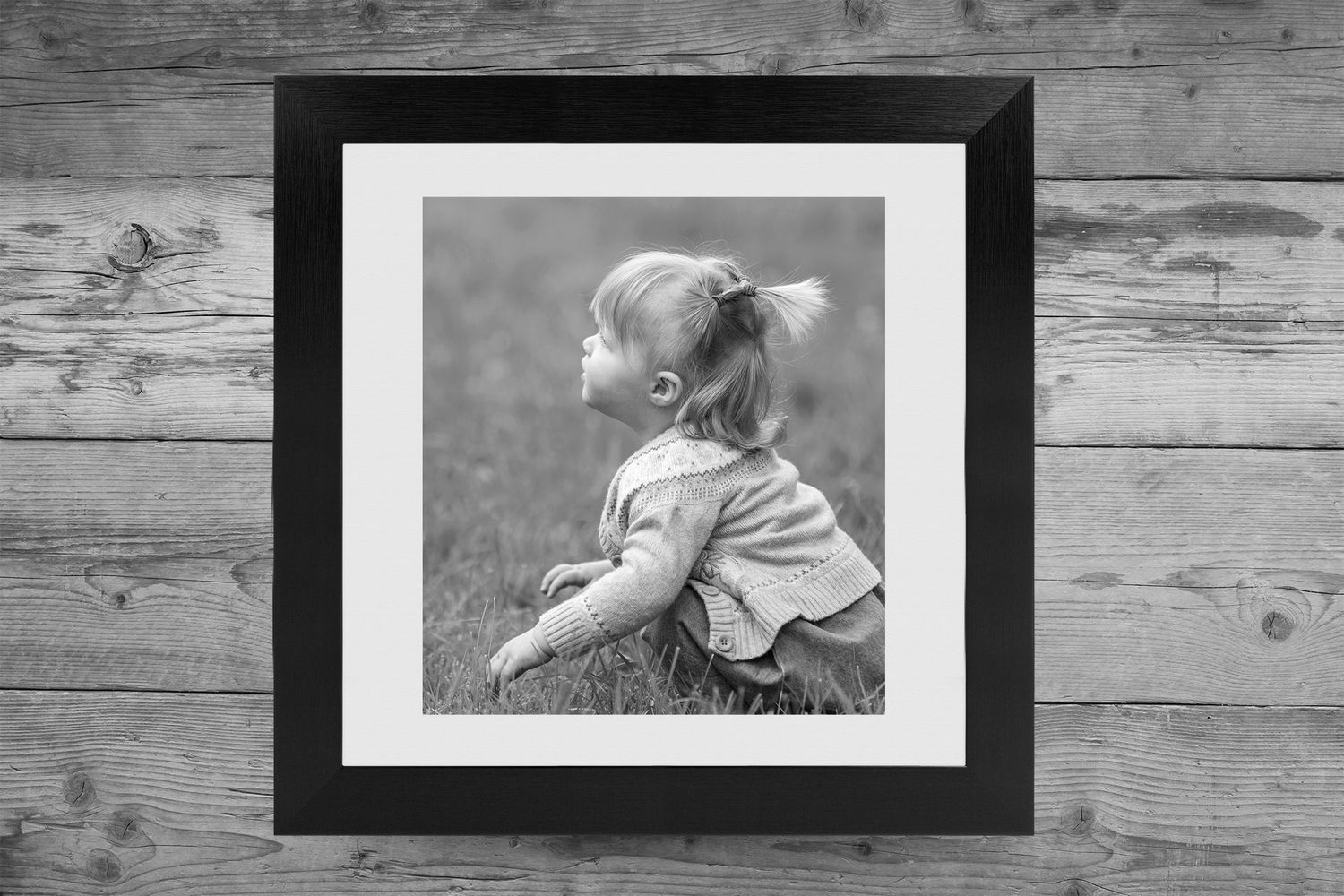 A row of black and white framed photographs displayed on a rustic wooden wall.