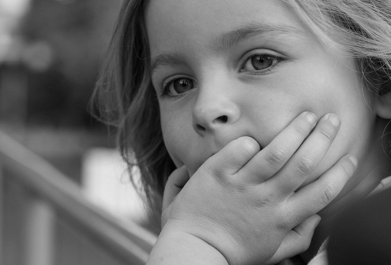 A black and white photo showing a child covering their mouth with their hand in different expressions.