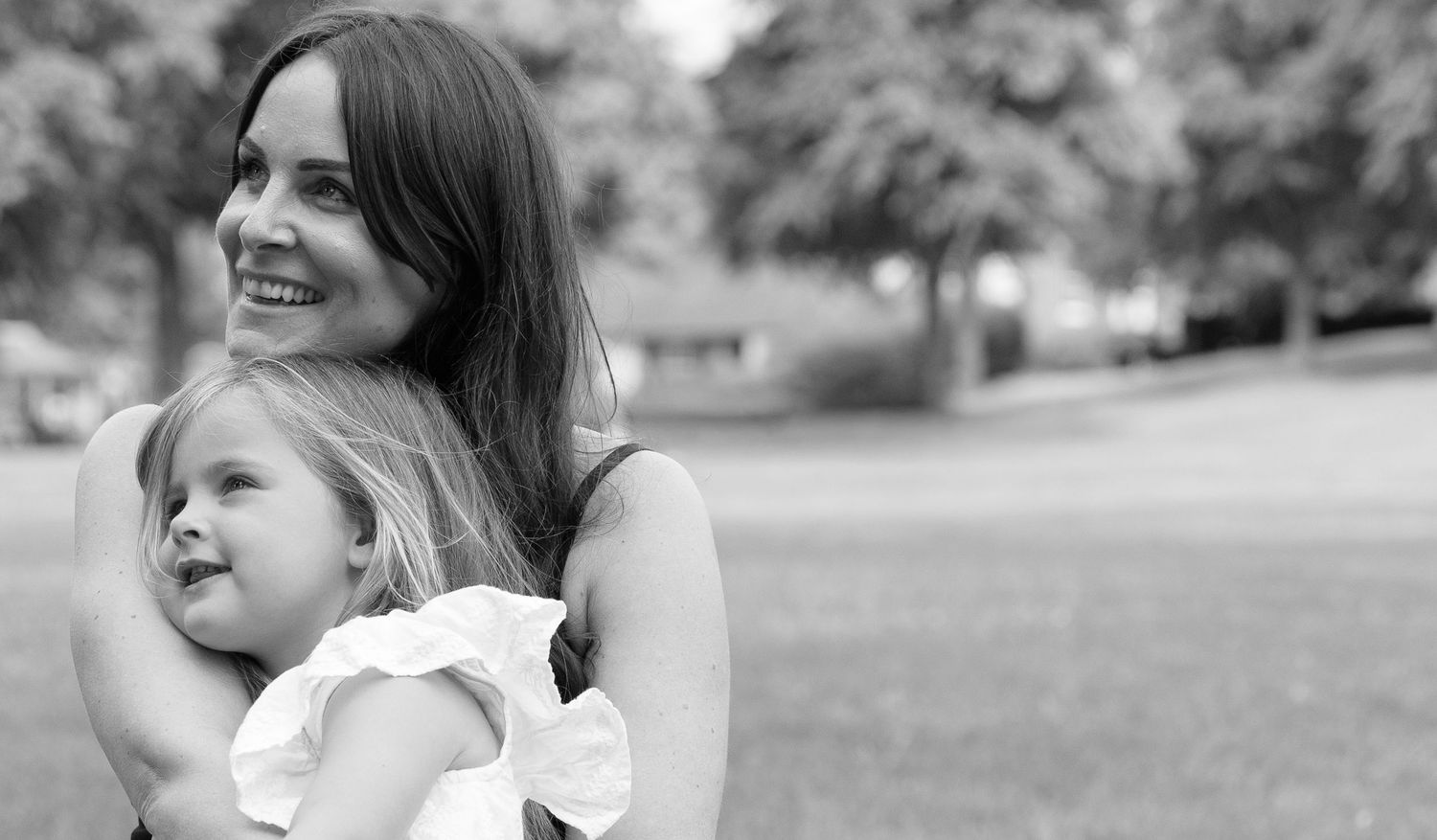 Candid black and white photo showing joyful parent-child moment outdoors.