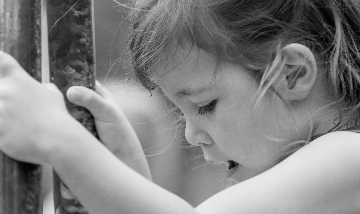 Black and white photo of a young child playing on the playing equipment at the playground.
