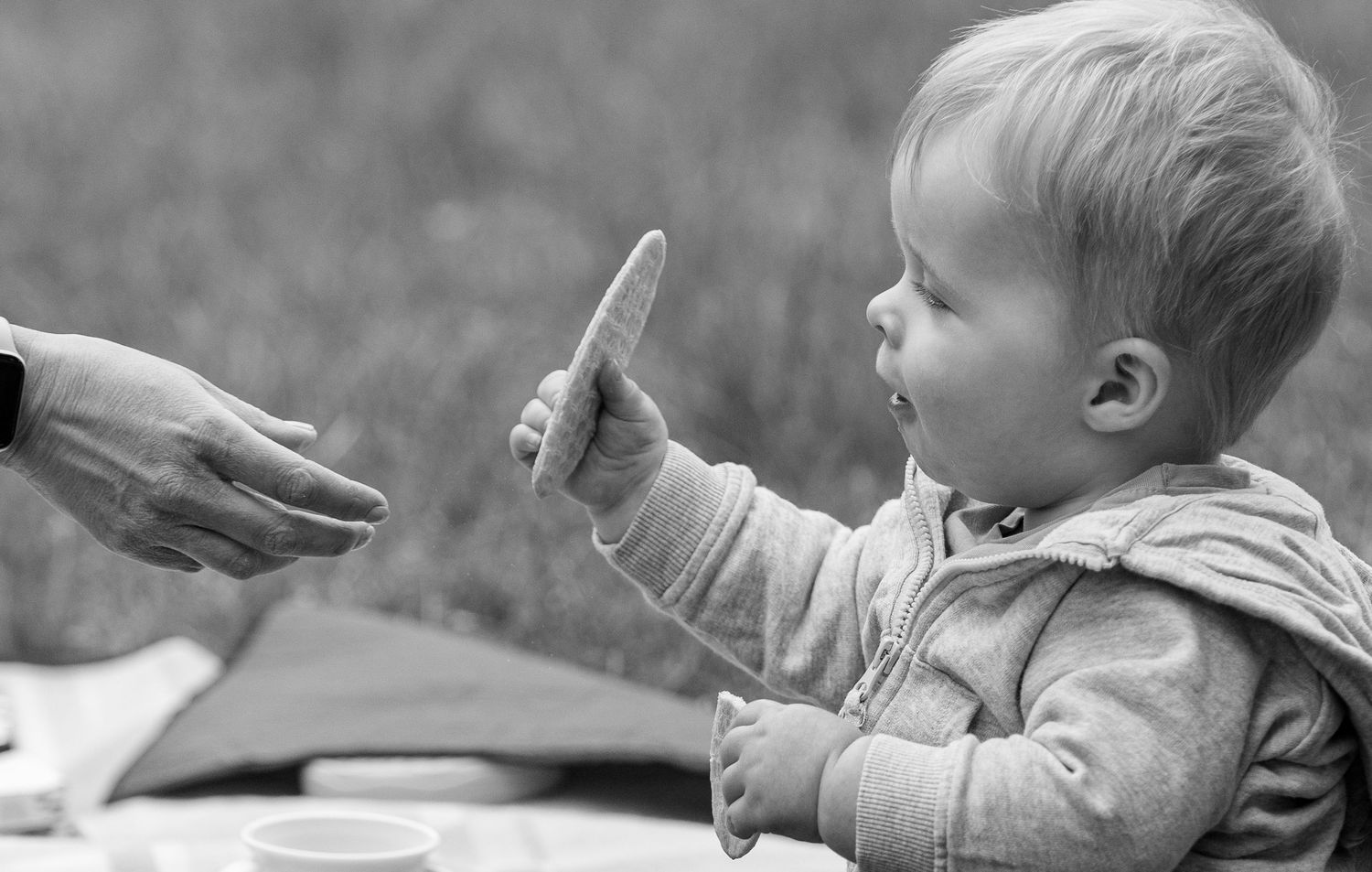 A black and white sequence of images showing a young child reaching for and holding various objects.