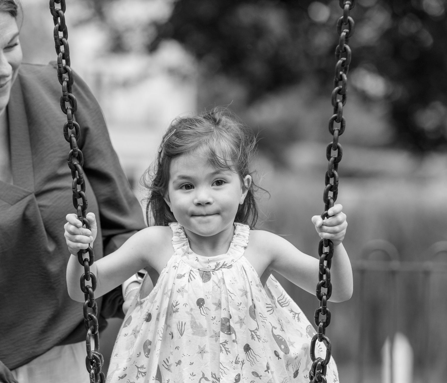 Black and white sequence of images showing a child swinging joyfully on a playground swing set.