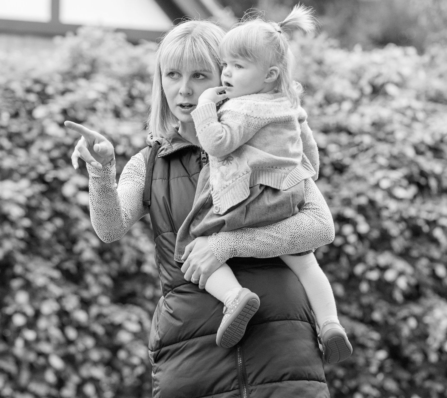 Black and white photo series showing tender moments between a parent and child in an outdoor garden setting.