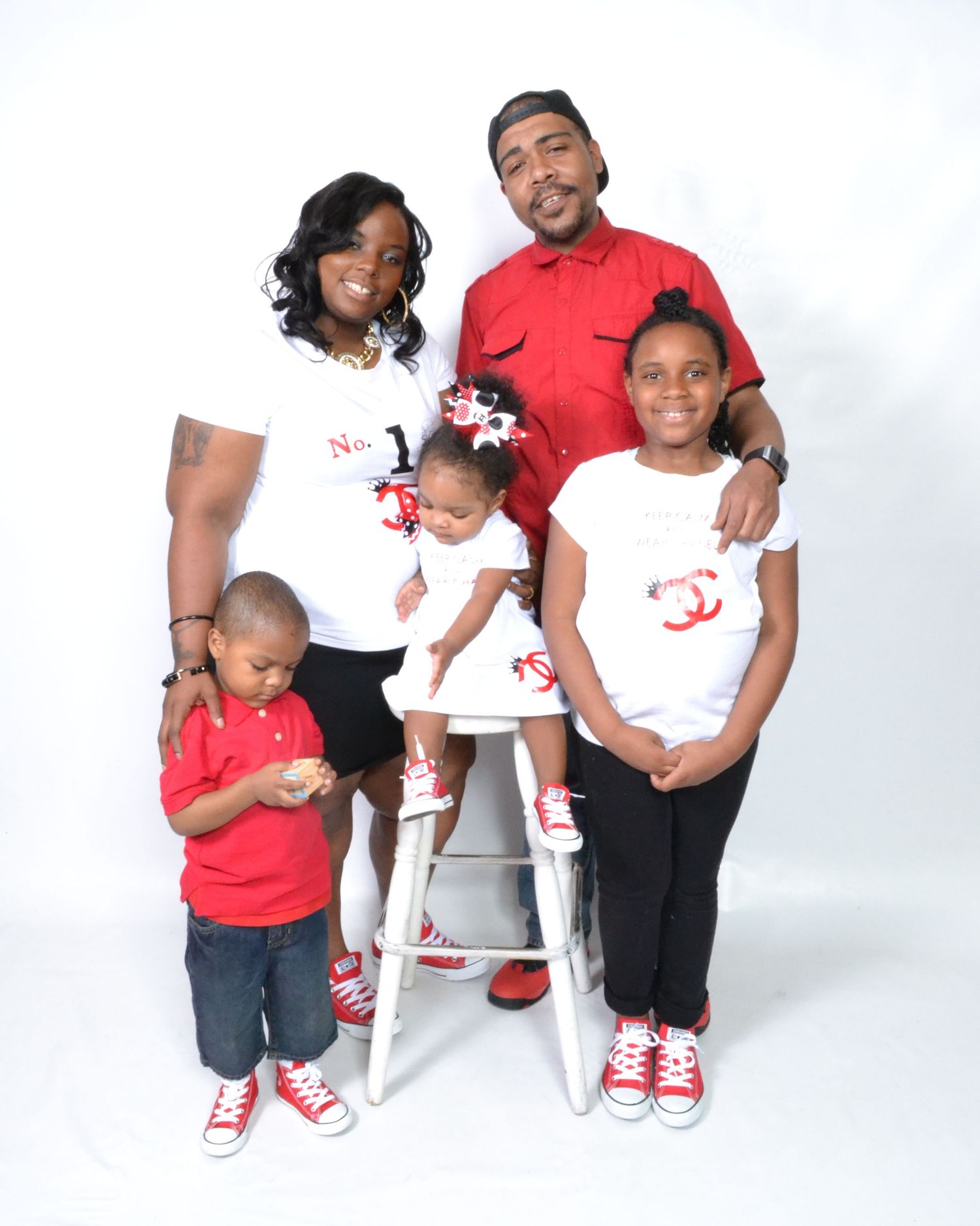 Family of five posing in matching red and white outfits with coordinating Converse sneakers for a professional studio portrait.