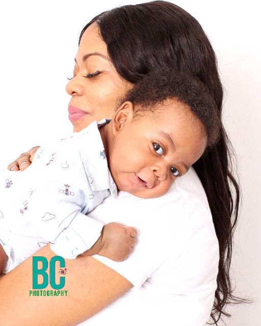 A mother tenderly holds her smiling toddler in a close-up portrait by BC Photography.