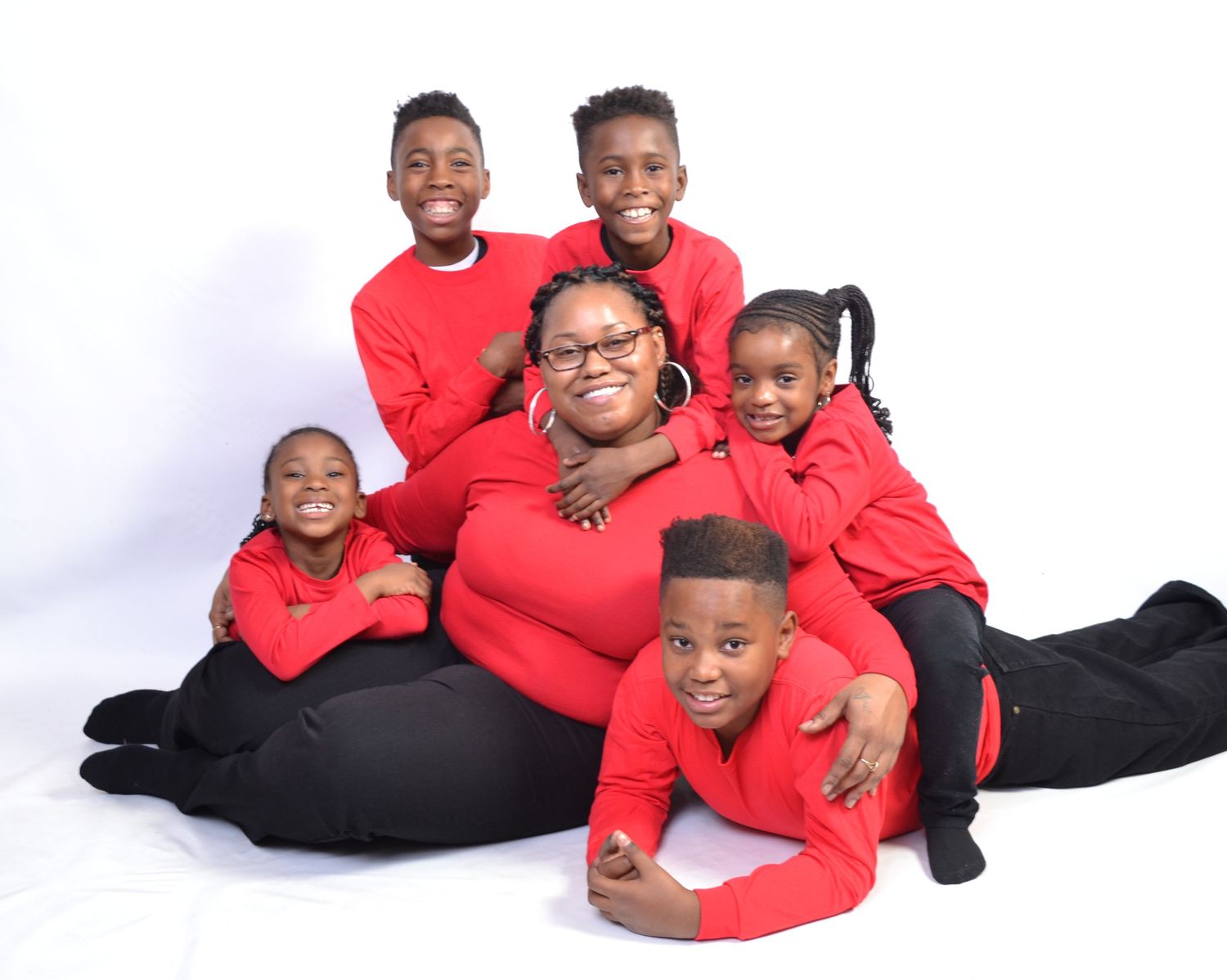 A joyful family of six wearing matching red and black outfits poses together for a professional portrait photo.