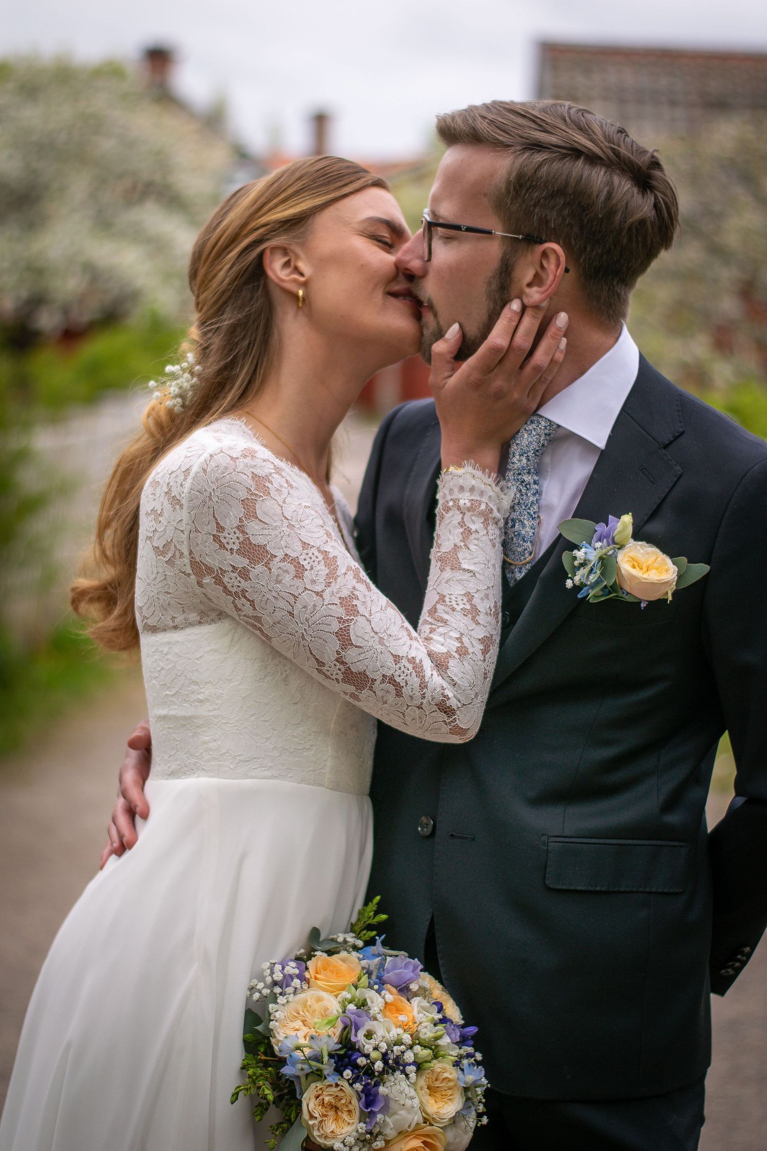 Brudpar vända mot varandra, där bruden har handen på brudgummens kind och lutar sig fram för att kyssa honom.