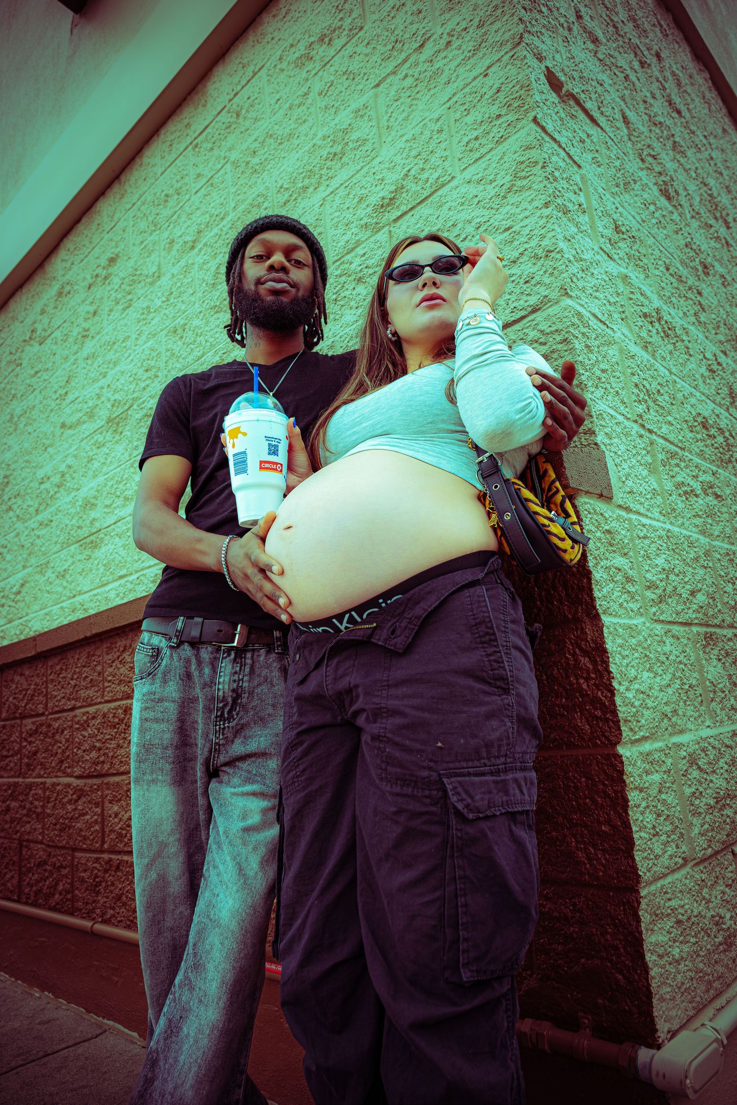 Two people stand against a wall with a green tinted lighting effect in a series of progressive shots.