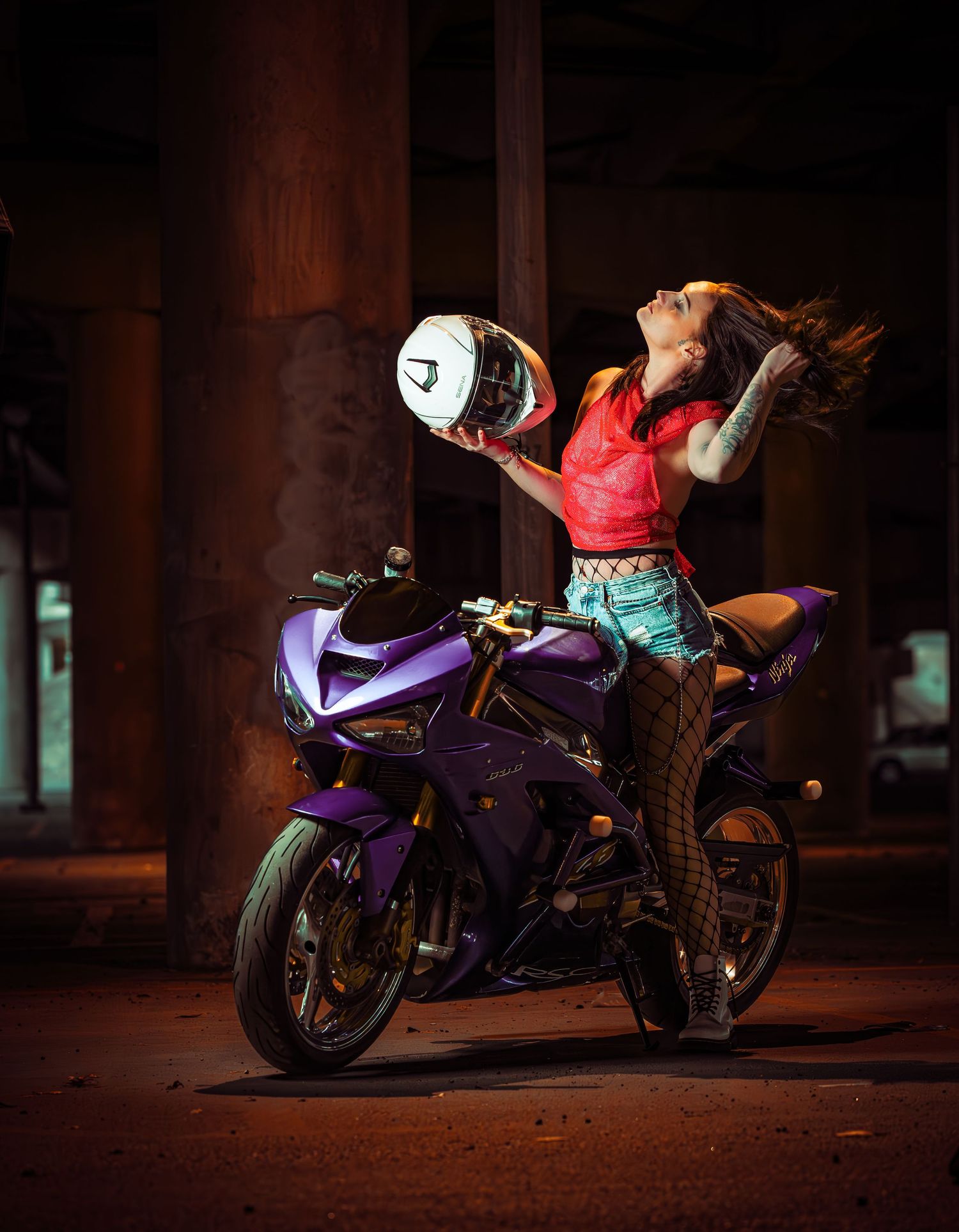 A purple sportbike motorcycle photographed at night in a dark parking garage setting.