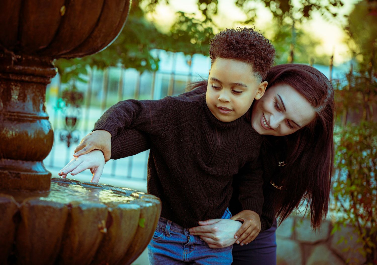 Mother and child share tender moments together in a natural outdoor setting during golden hour.