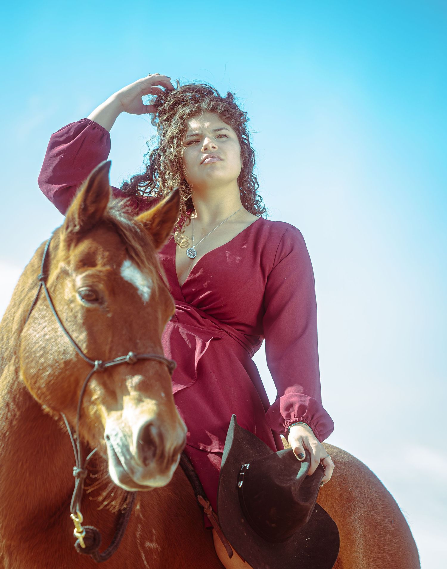 A series of four photos showing someone in a red jacket riding a chestnut horse against a bright blue sky.