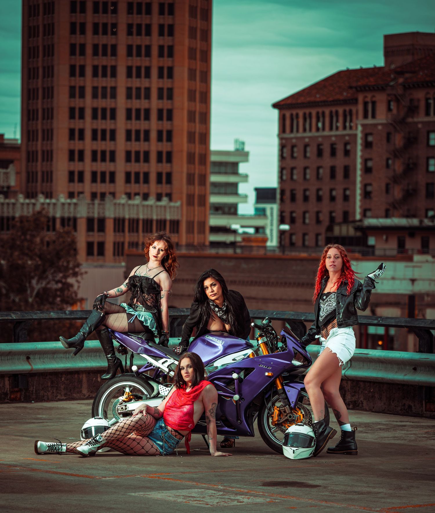 Urban rooftop scene with motorcycles and group posing together at sunset with city buildings in background.