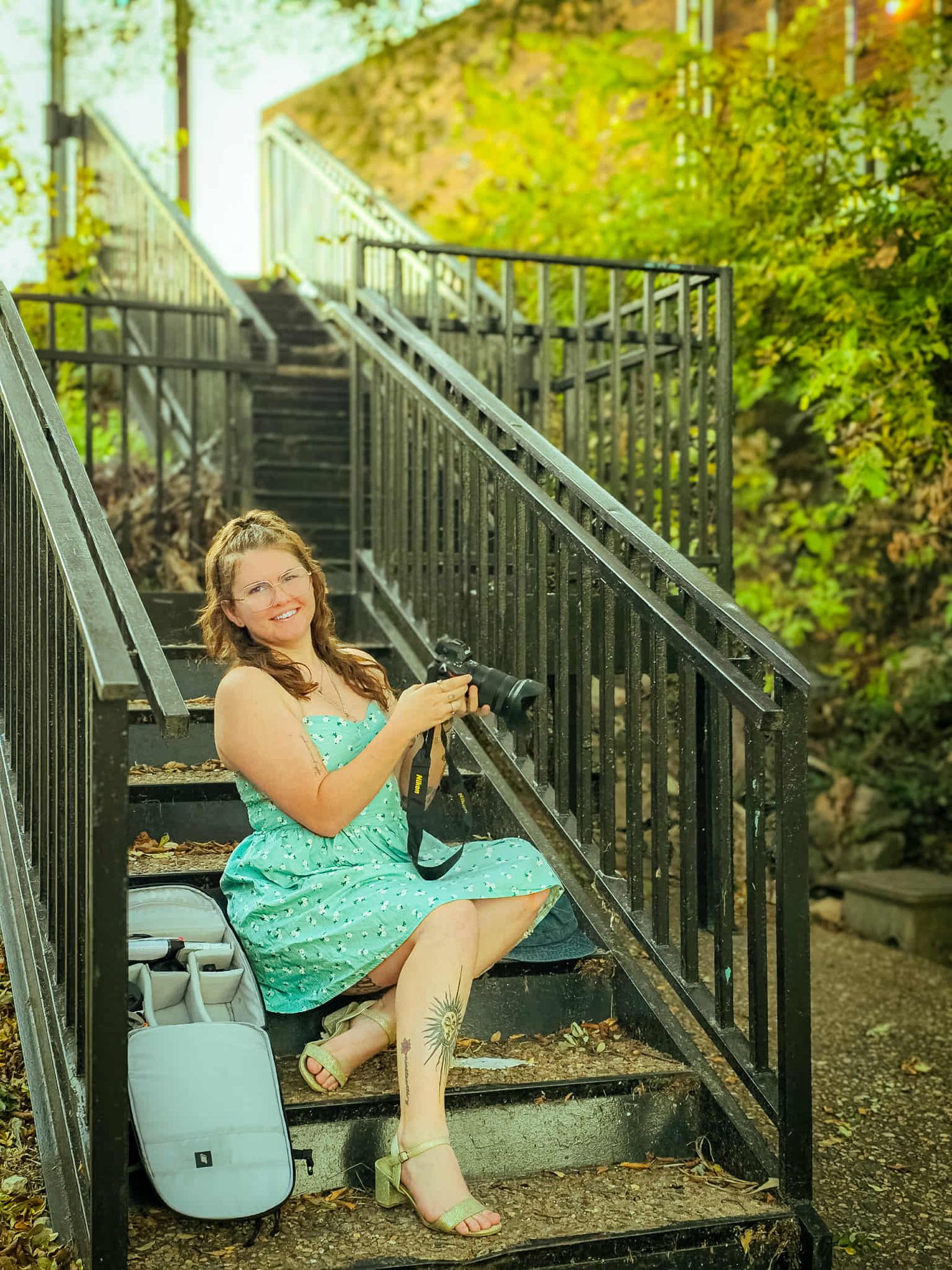 Person in turquoise dress posing on outdoor metal stairs with natural lighting.