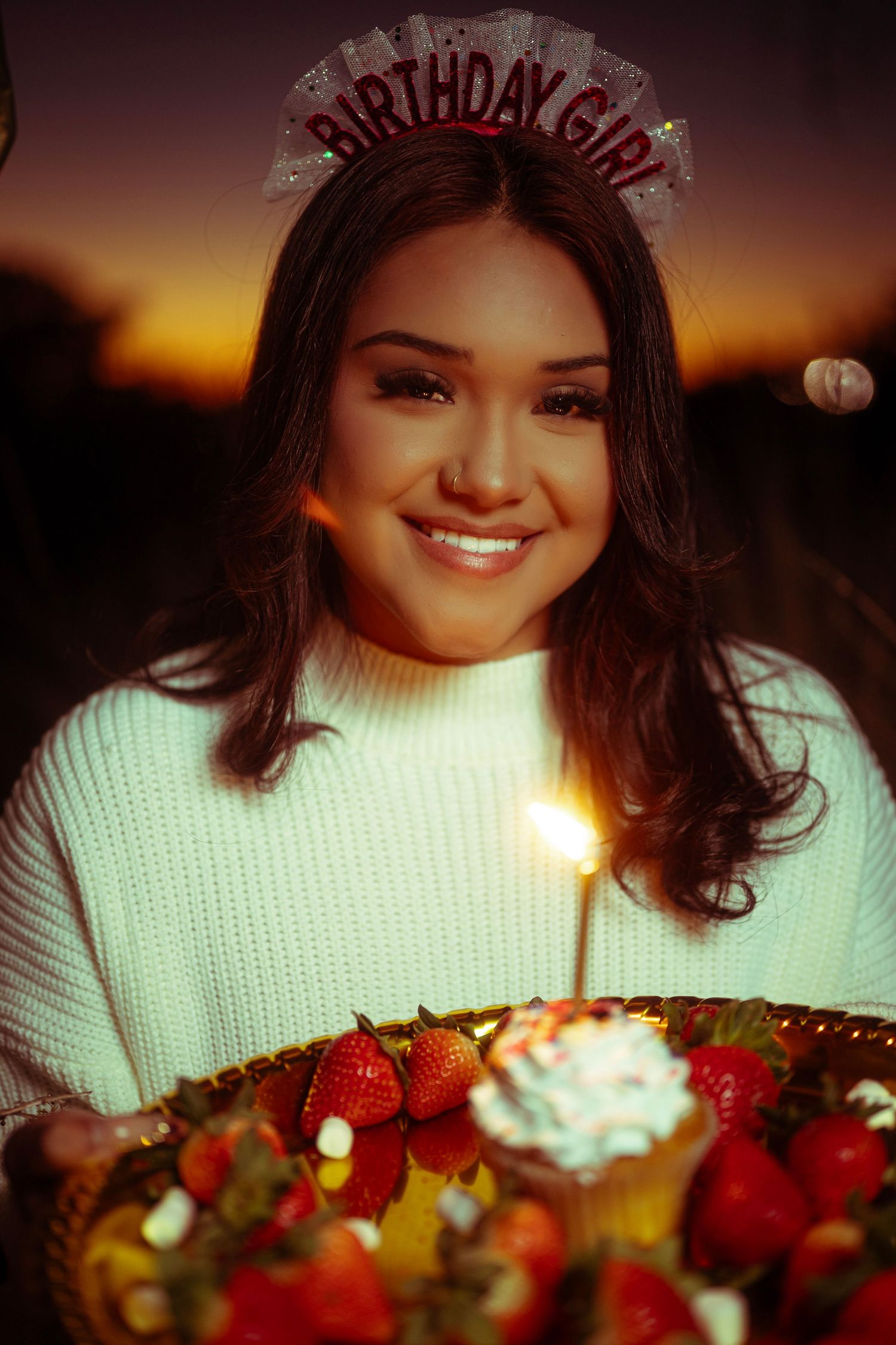 A birthday celebration scene with fresh strawberries and whipped cream dessert illuminated by warm sunset lighting.