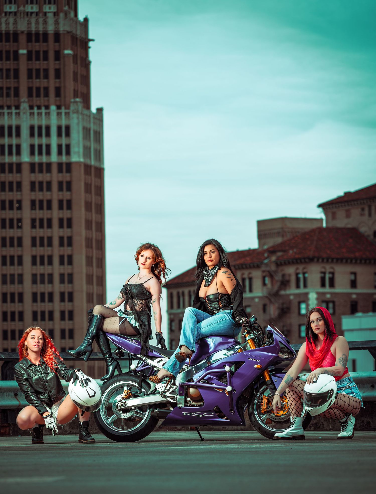 Urban motorcycle photoshoot with four people posing with sport bikes against city buildings in teal tinted lighting.