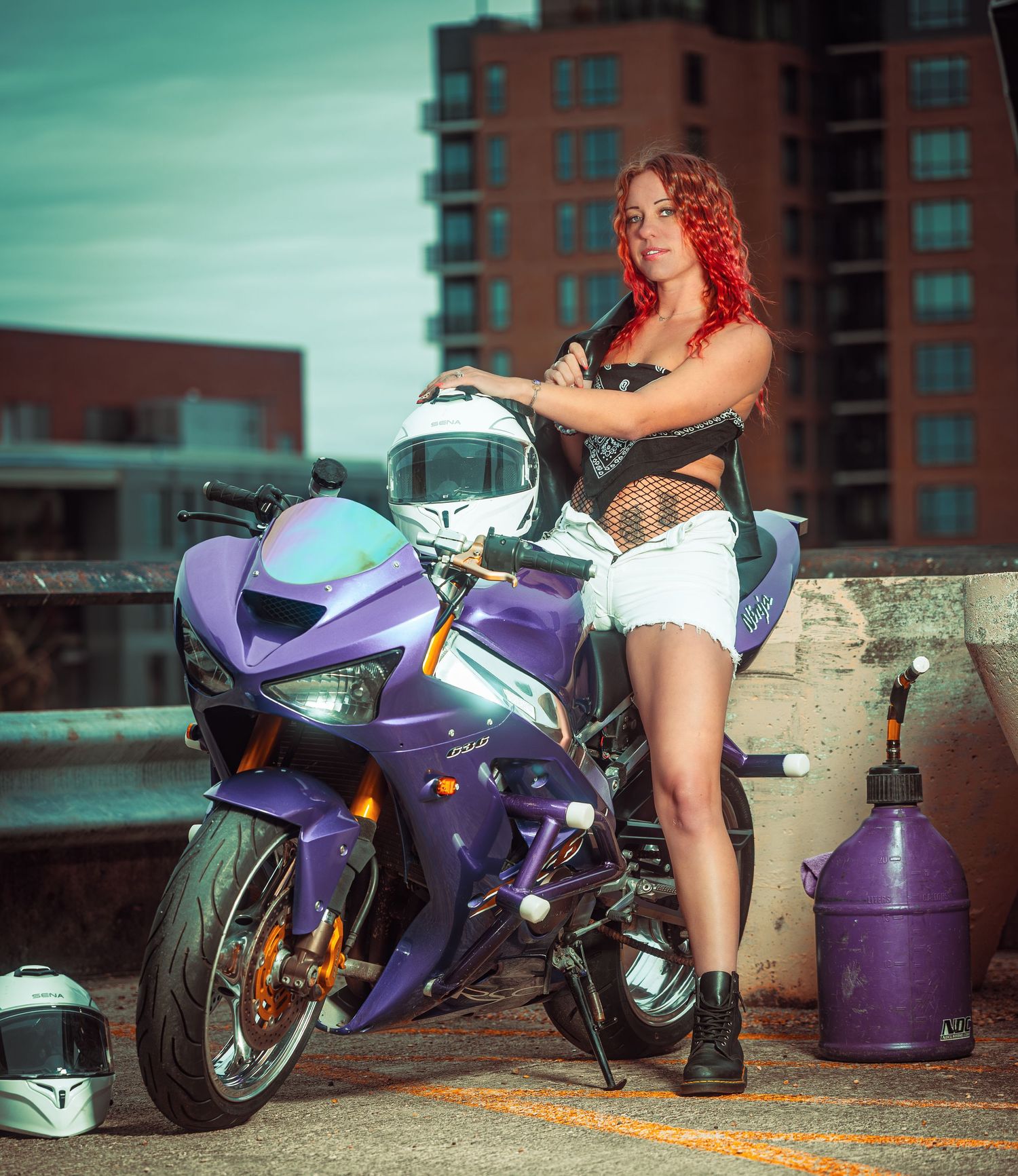 A purple sport motorcycle displayed in an urban setting with brick buildings in the background.