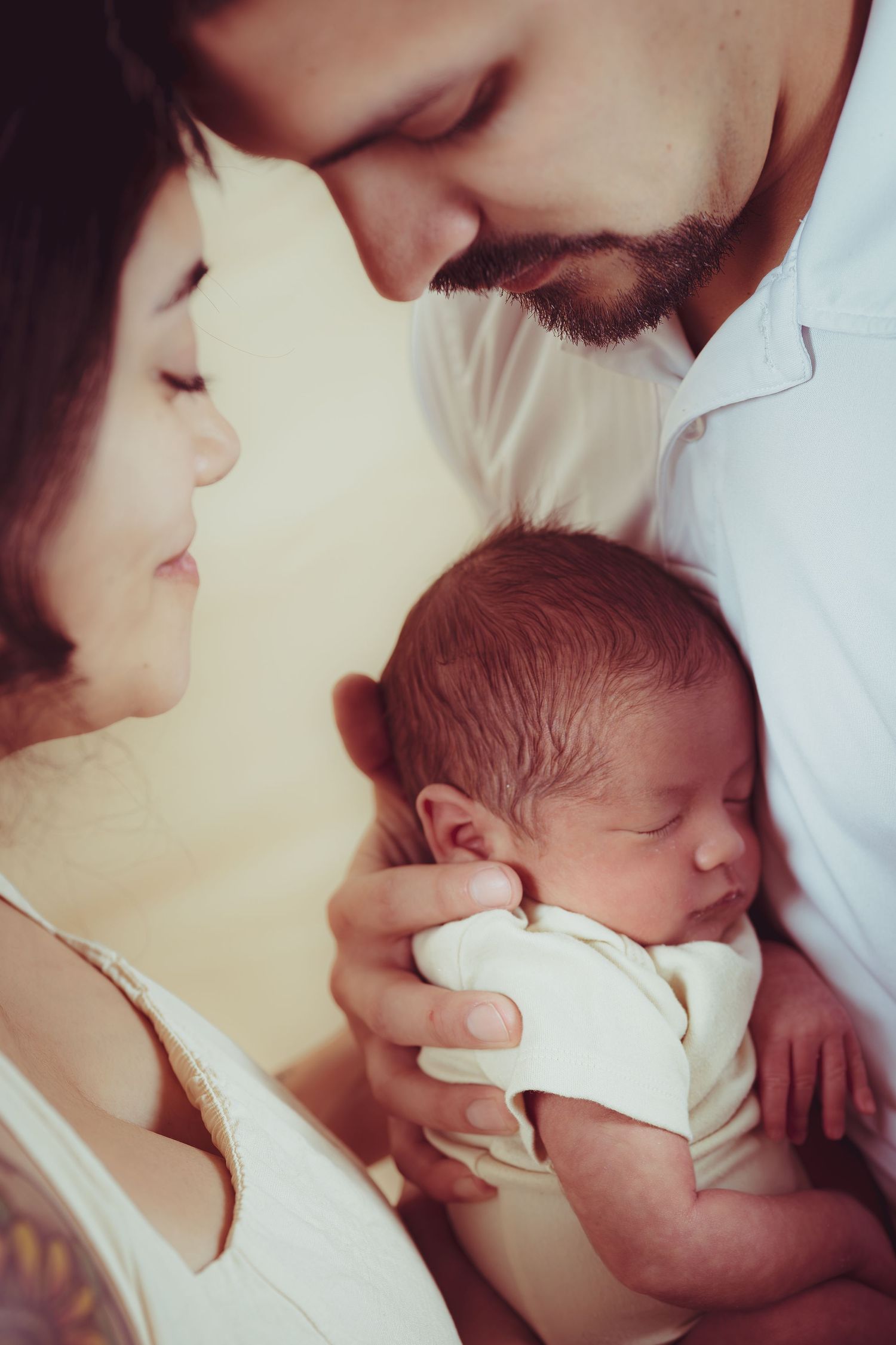 Parents tenderly holding their sleeping newborn baby, sharing an intimate family moment together.