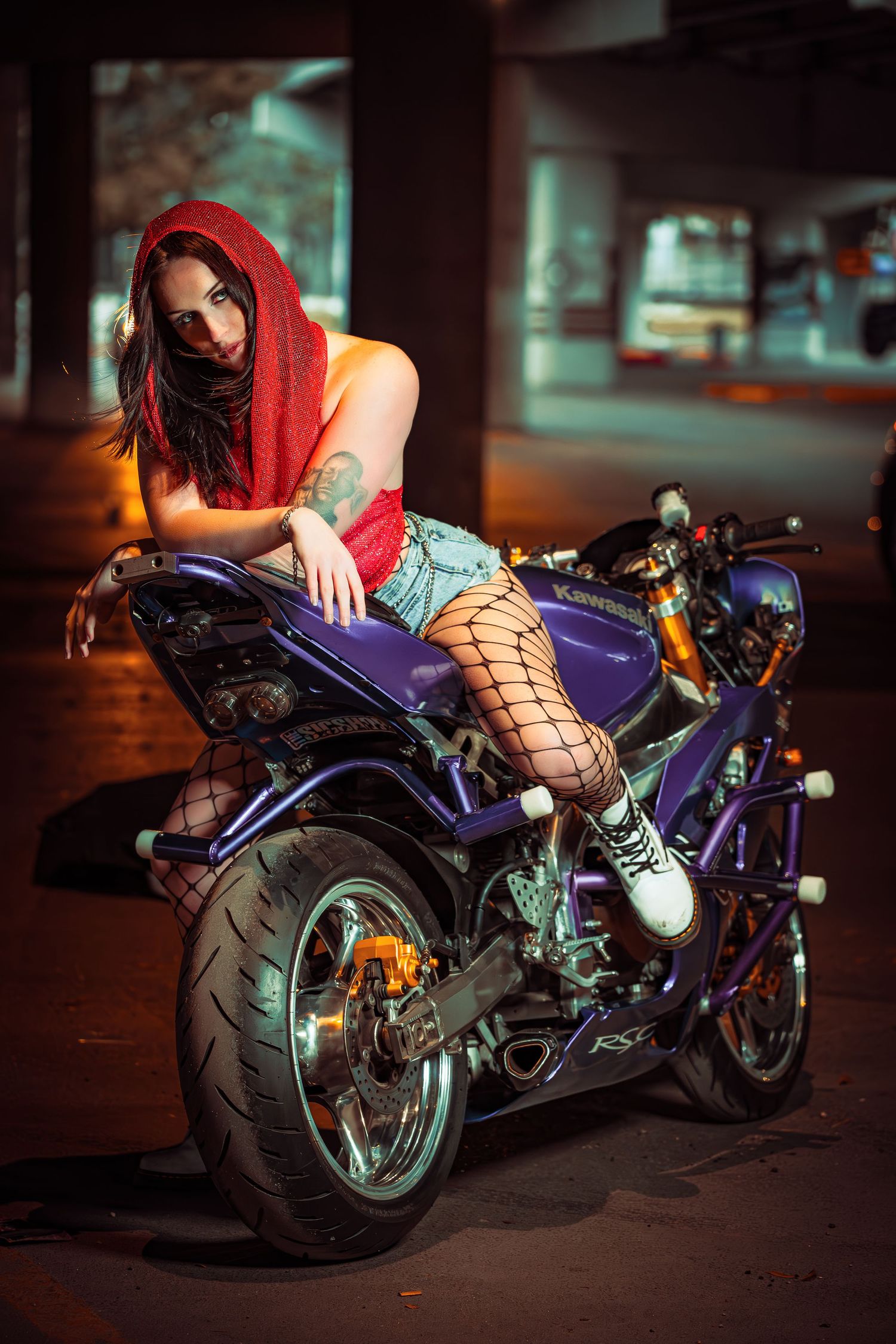 Purple custom motorcycle photographed at night with dramatic lighting and fishnet details.