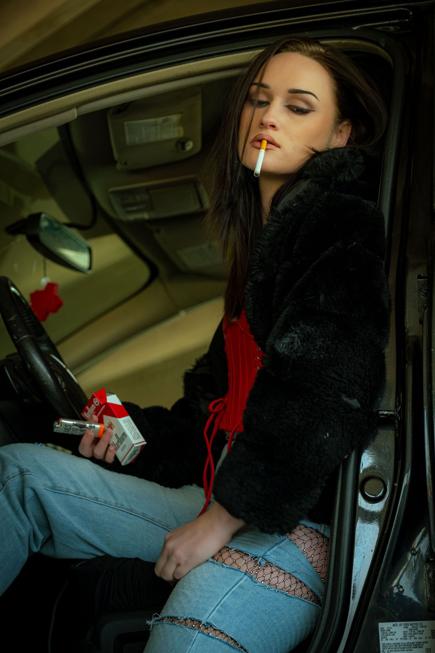 Artistic photoshoot inside a car featuring moody lighting and casual denim style.