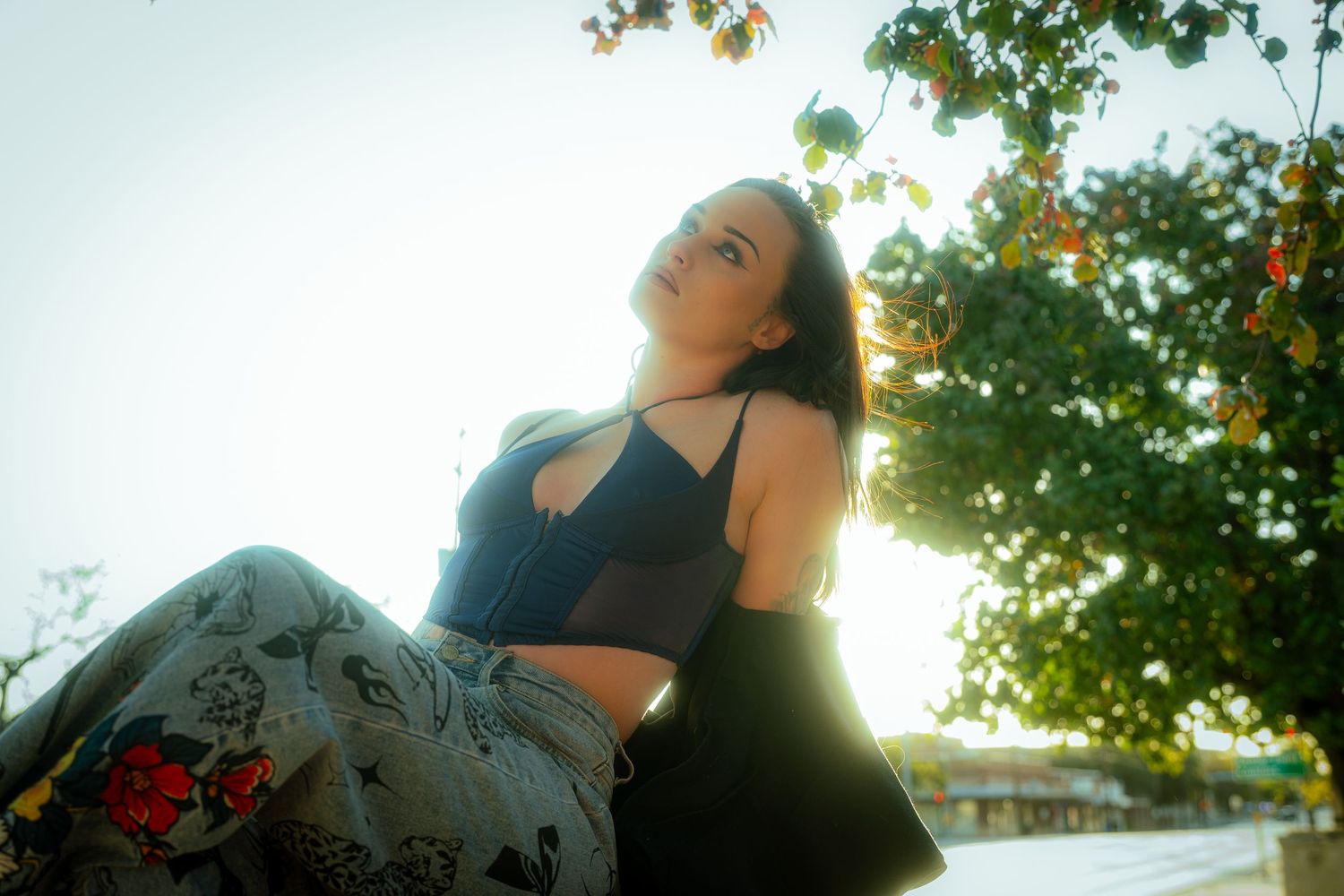 Artistic portrait shot against sunlit trees creating a dreamy backlit effect.