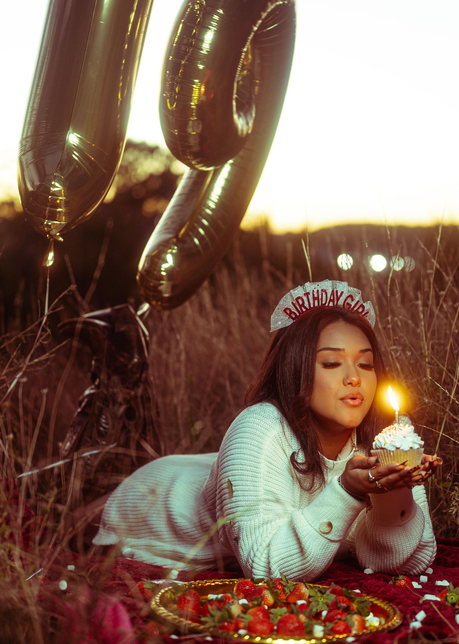 Person lying on grass surrounded by twinkling holiday lights creating a magical winter scene outdoors.