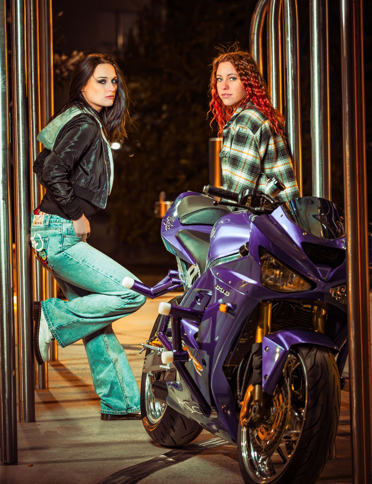 A purple motorcycle parked in an industrial setting with reflective metal columns in the background.