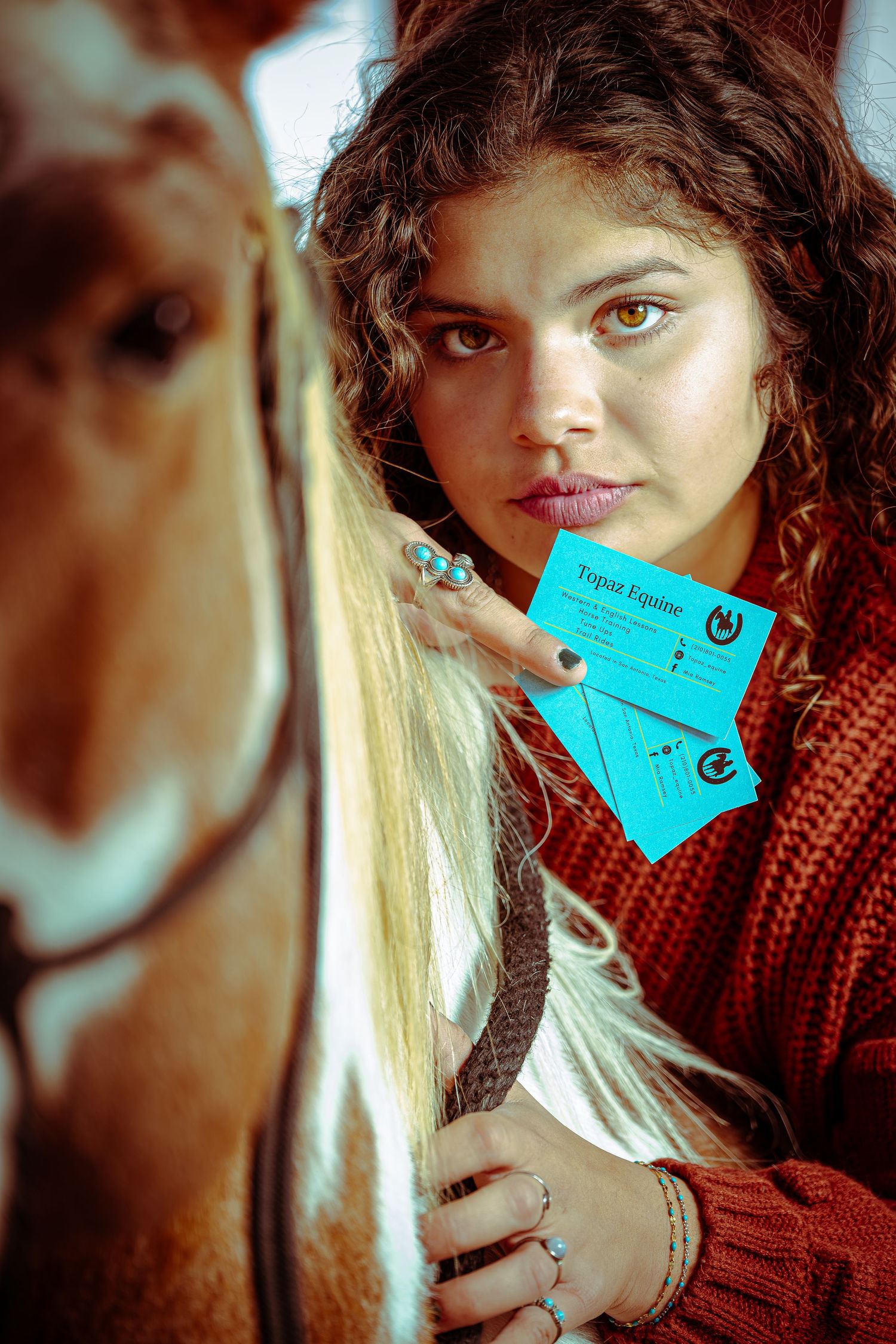 Person in a red knit sweater holds a blue ticket or card against a soft focus background.