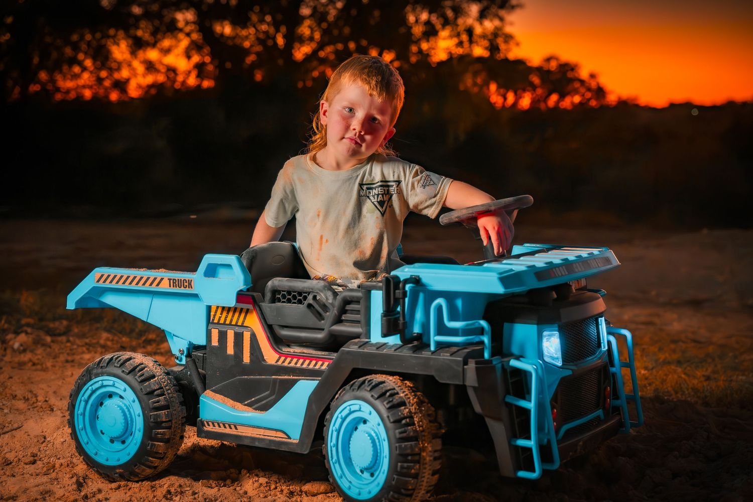 Blue industrial toy truck photographed in dramatic sunset lighting.