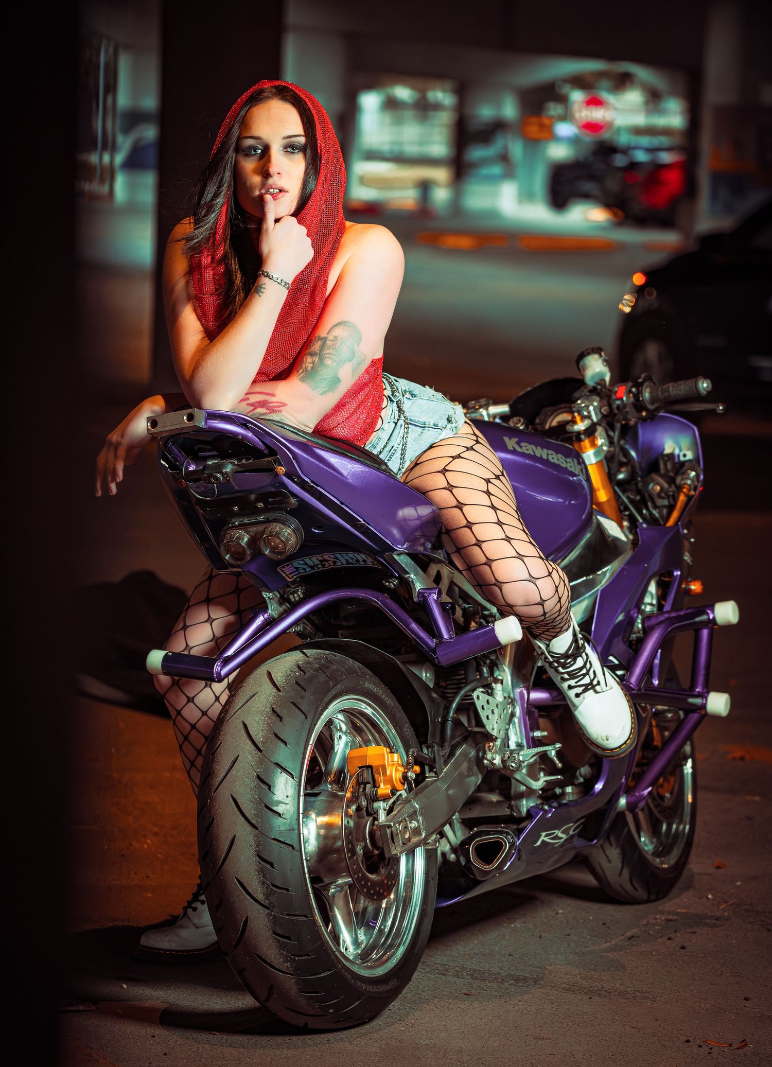 A purple custom motorcycle with chrome accents photographed in an urban nighttime setting.