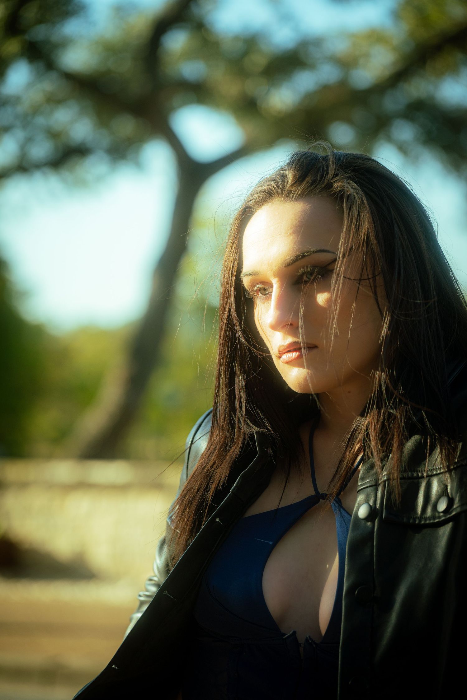 Outdoor portrait with natural sunlight filtering through trees creating warm tones.