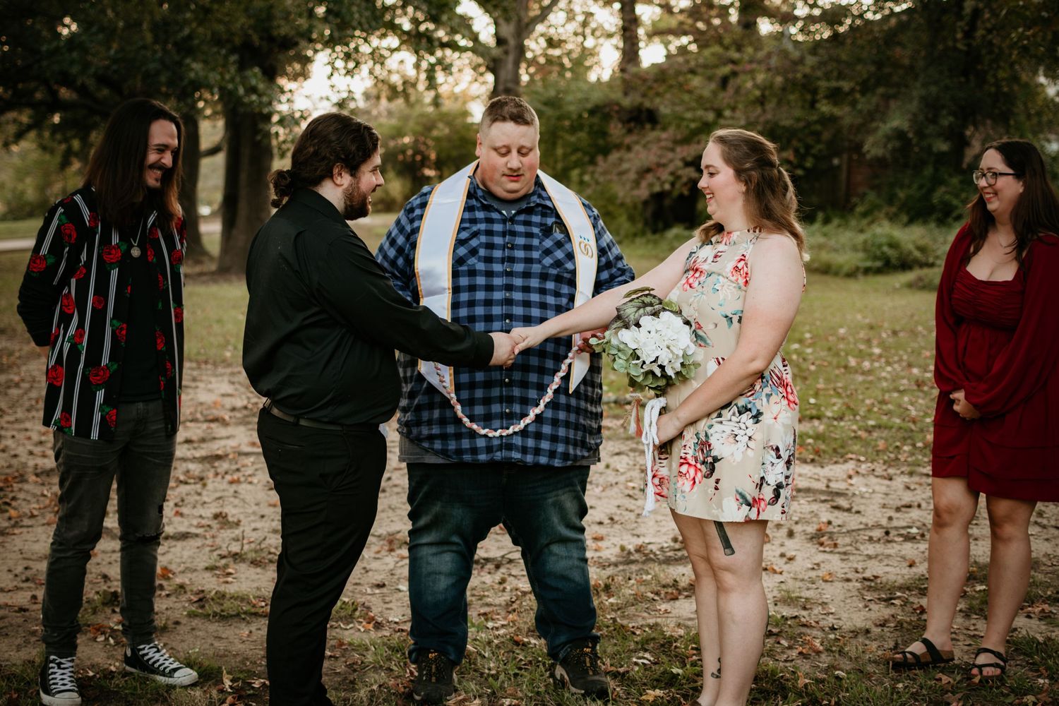Wedding between a man and a woman, they are holding hands as the officiant speaks.