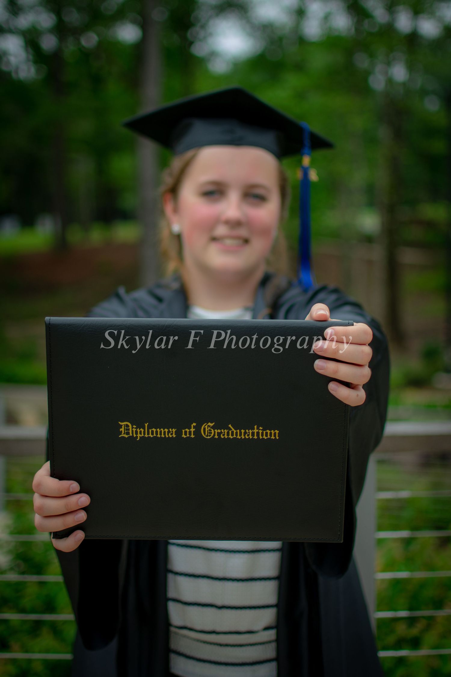 A girl can be seen smiling while holding a diploma out in front of her.