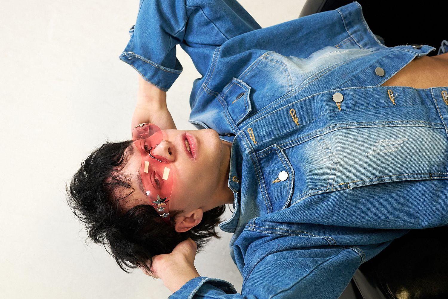 A person in a denim jacket lying down with a bloody nose effect in a sequence of three similar poses.